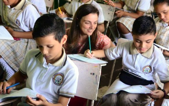 Secretaria de Educación observando a niño en salón de clases.