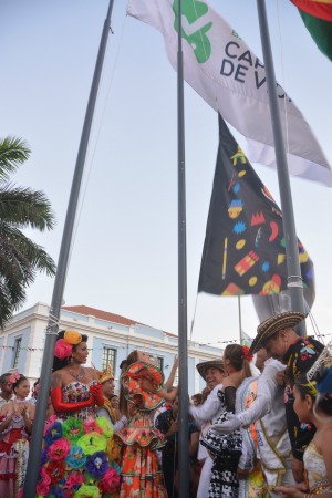 Personas disfrazadas izando la bandera del carnaval.