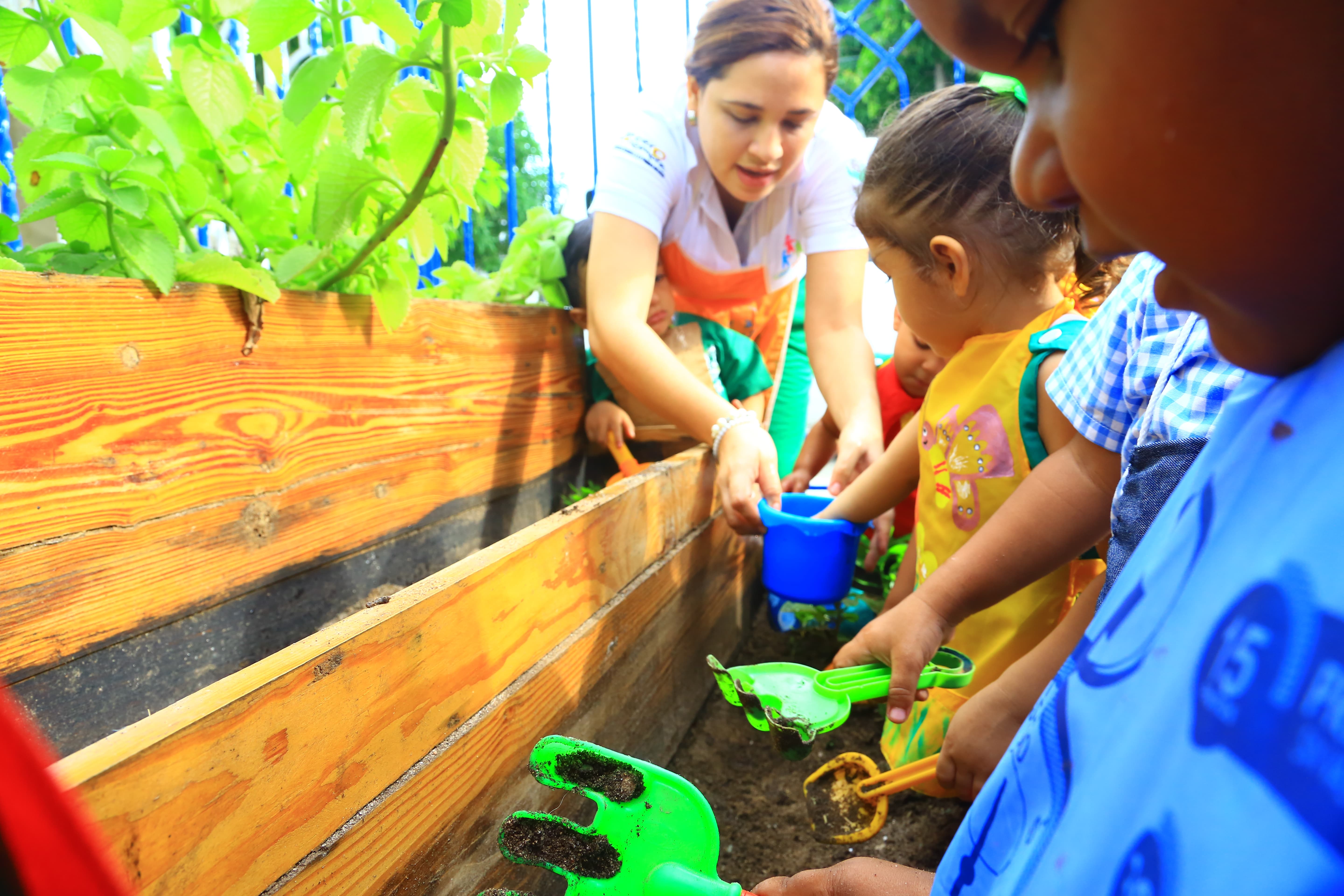 Educadora y niños en actividad de siembra de plantas.