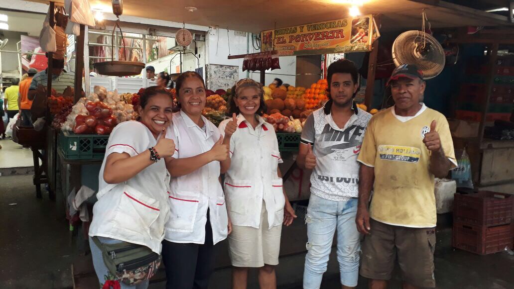 Familia posando para foto en puesto de verduras