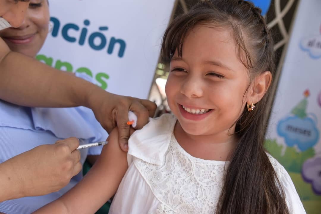 Niña sonriente recibiendo vacuna en el brazo