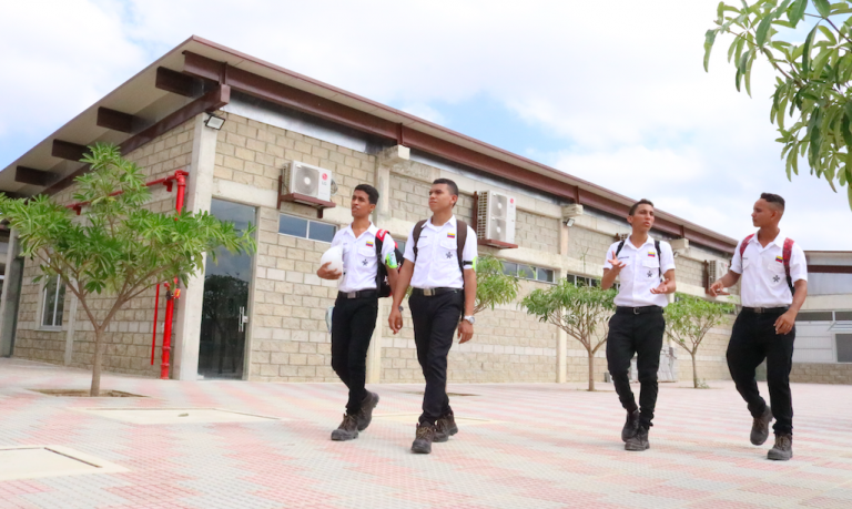 Cuatro estudiantes caminando frente a su escuela.