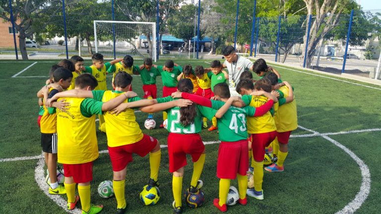 Equipo de futbol infantil reunidos en mitad de cancha de futbol