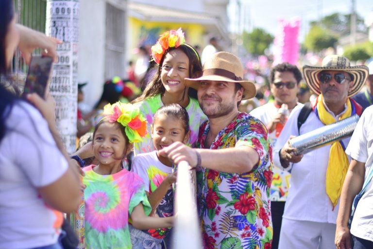 Alcalde salaudando a niños en mitad del desfile