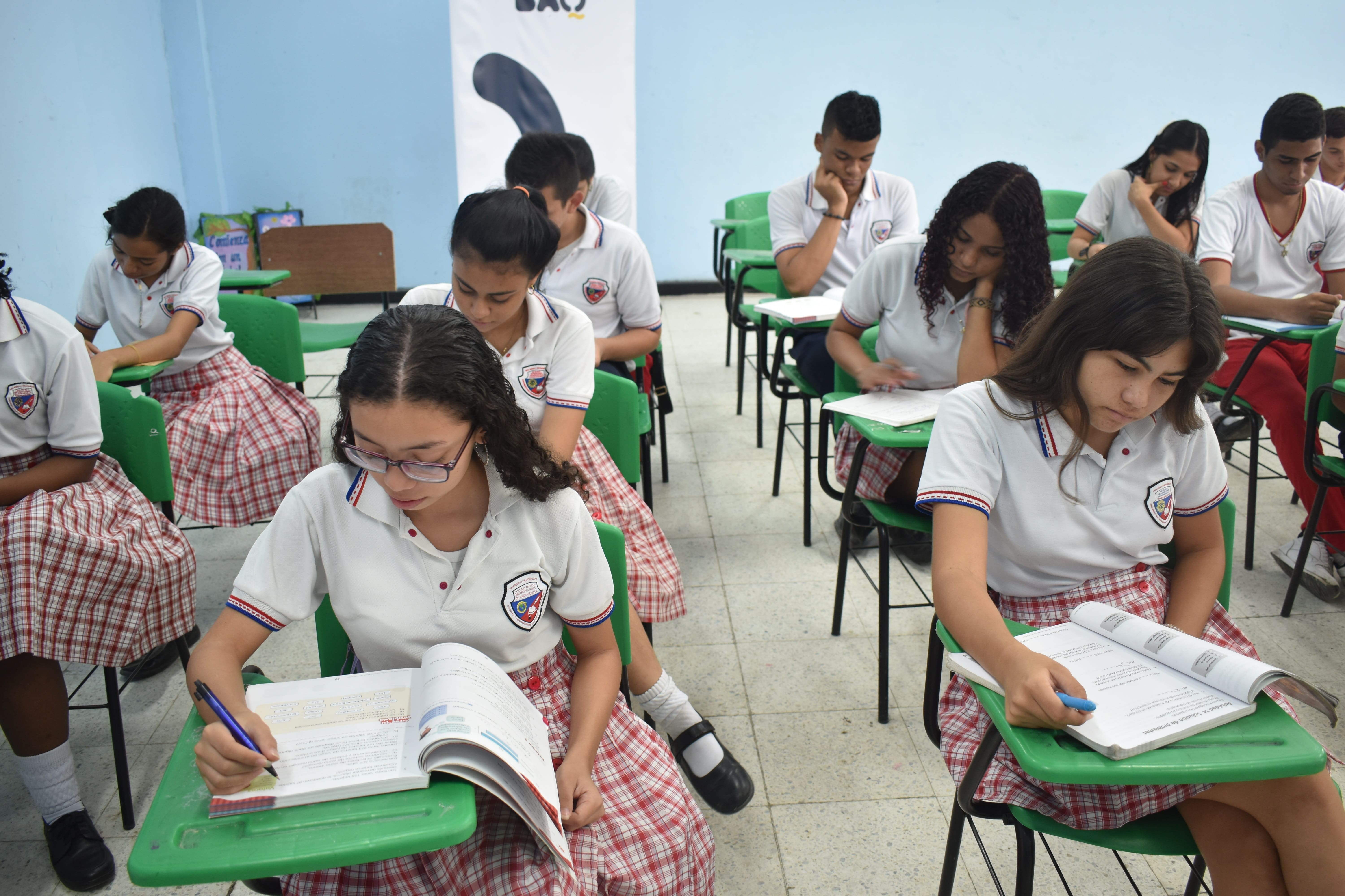 Estudiantes en aula de clases escribiendo en sus cuadernos