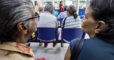 Dos mujeres sentadas en la oficina de atención de subsidios .