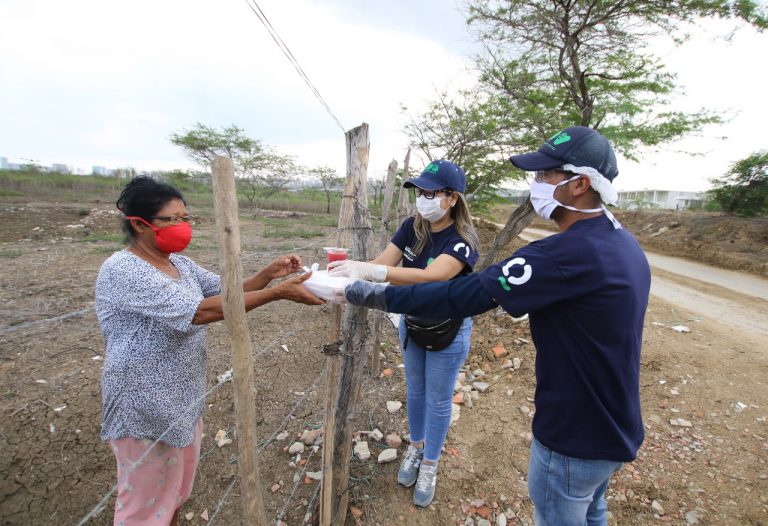 Brigadistas de salud entregando alimentos a adulta mayor en zona rural