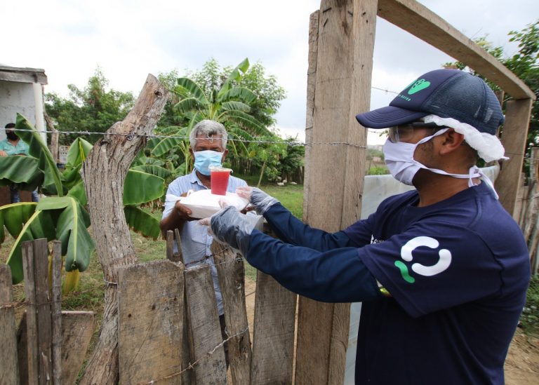 Brigadista de salud entragando alimentos a adulto mayor