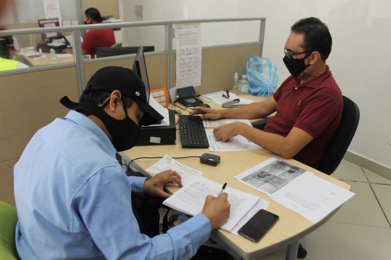 Dos hombres en oficina trabajando frente a computador