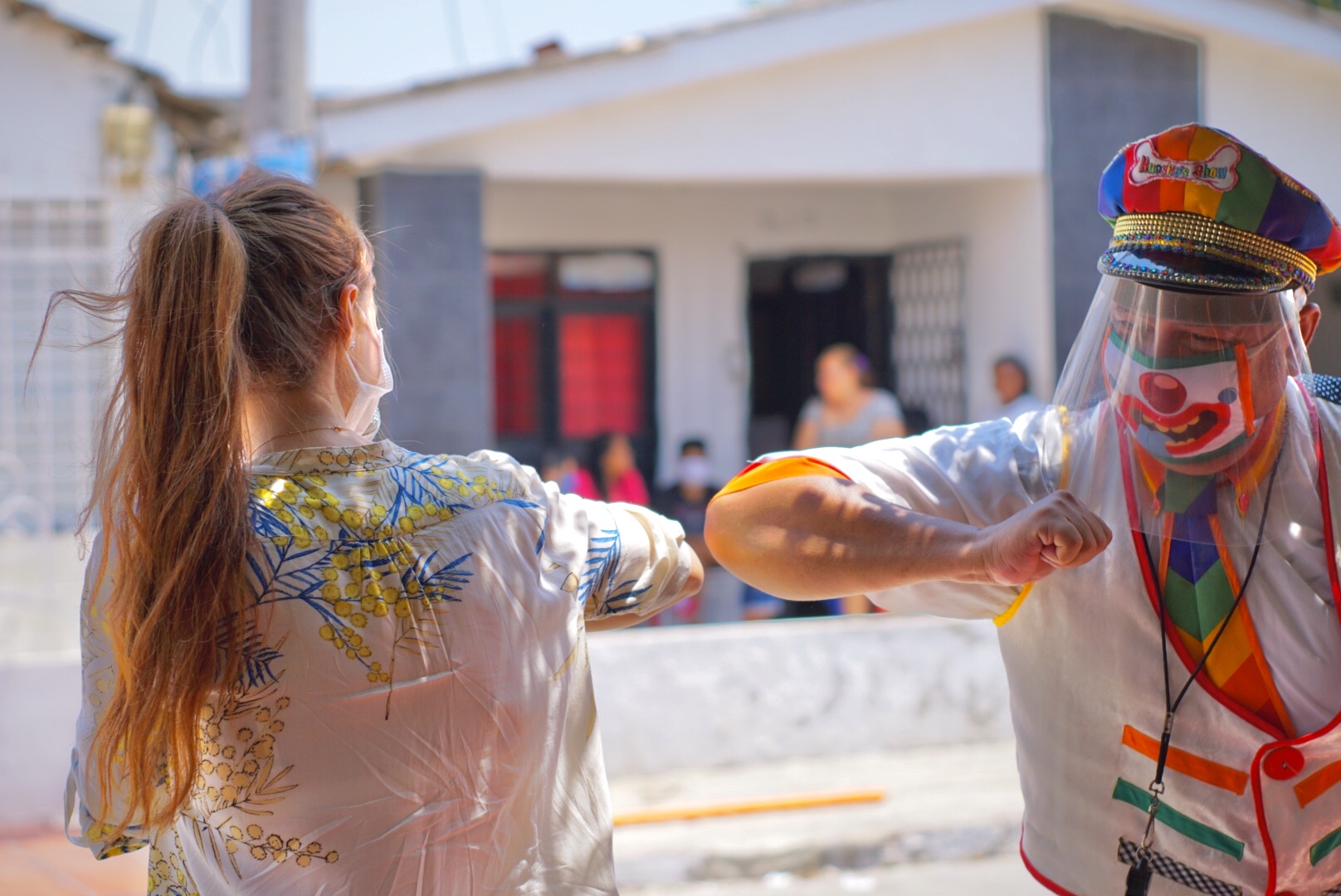 Gestora social saludando de codo con un clown