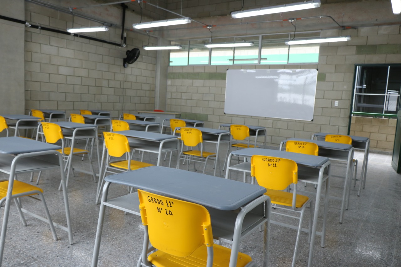 Vista de un salon de clases con los pupitres vacios