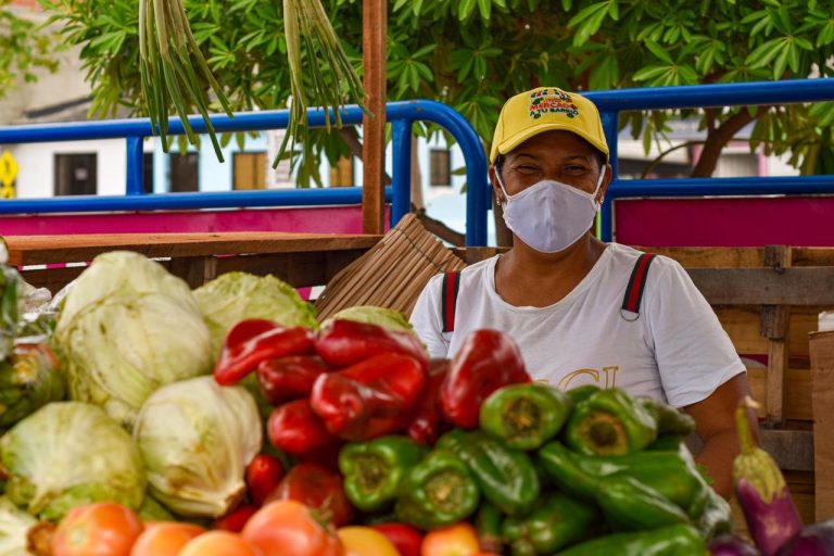 vendedora frente a puesto de verduras