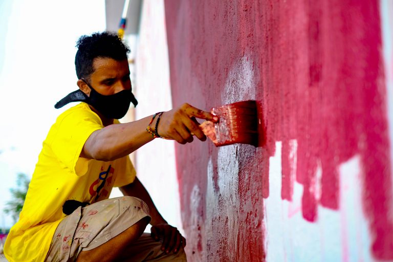 Joven pintando pared de rojo