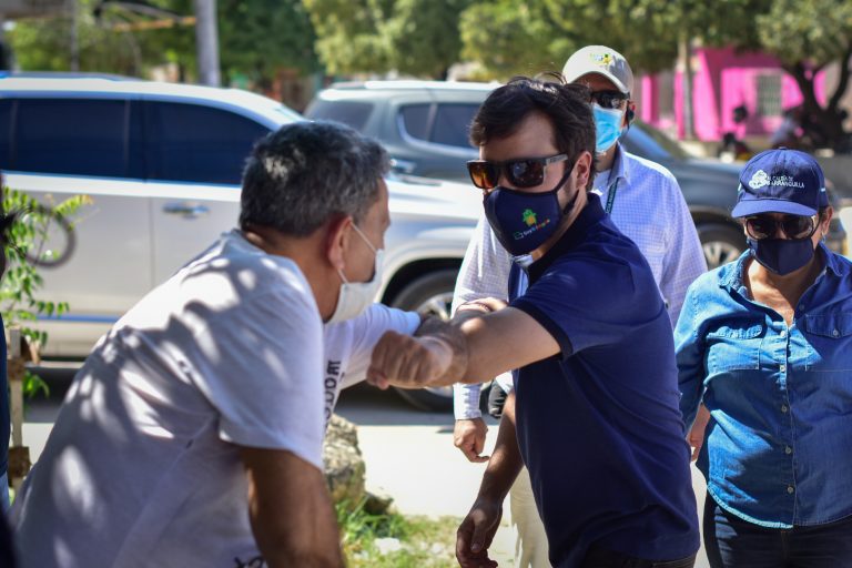 Alcalde Pumarejo saludando de codo a ciudadano en la calle.