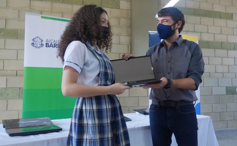 Estudiante recibiendo laptop de manos del Alcalde Pumarejo