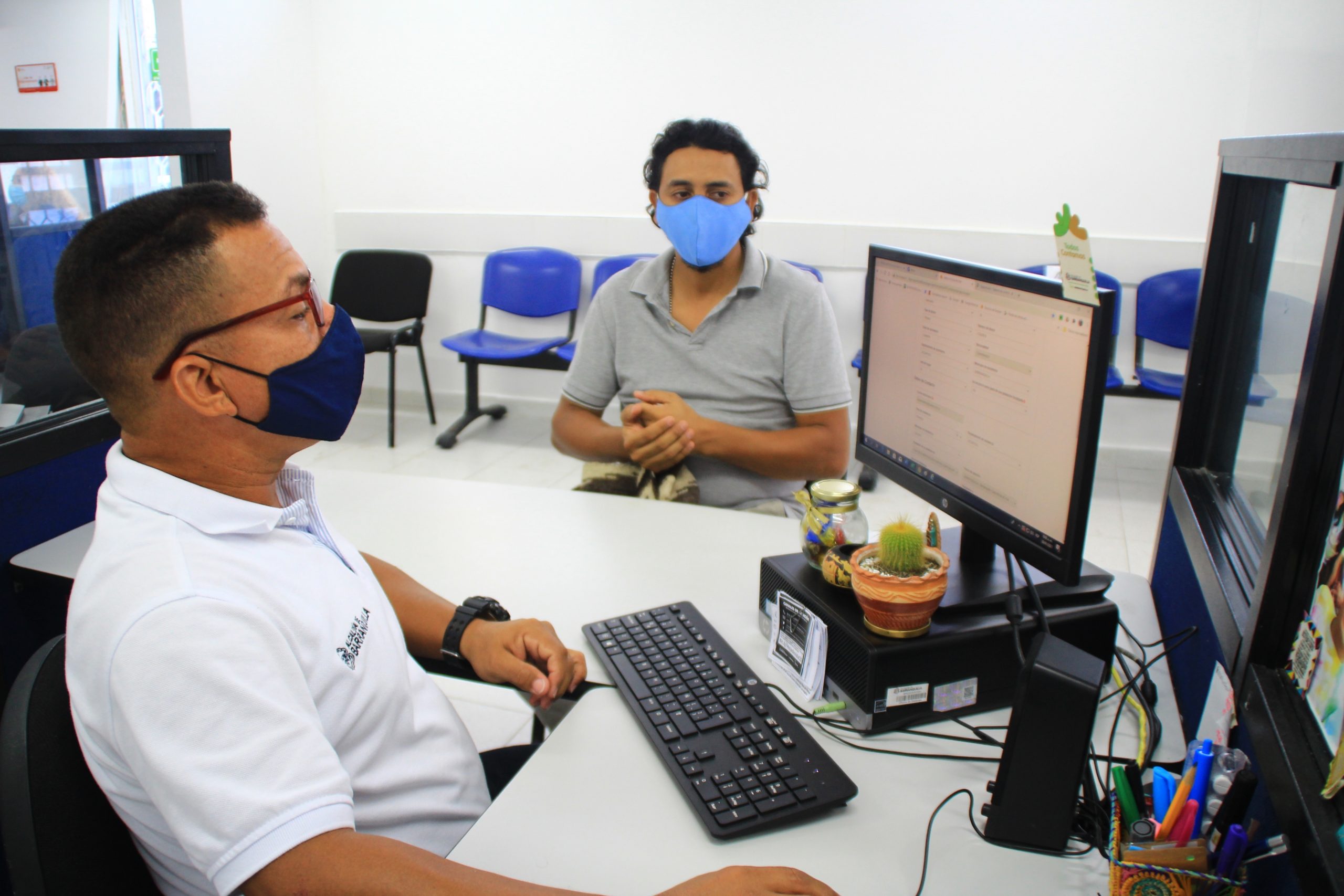 Hombre sentado frente a un computador , atiende a una mujer