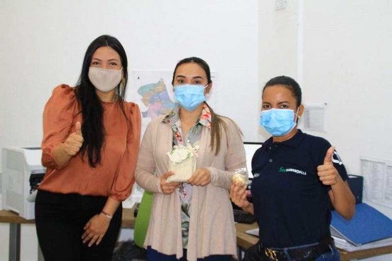 Tres mujeres con mascarillas recibiendo obsequio