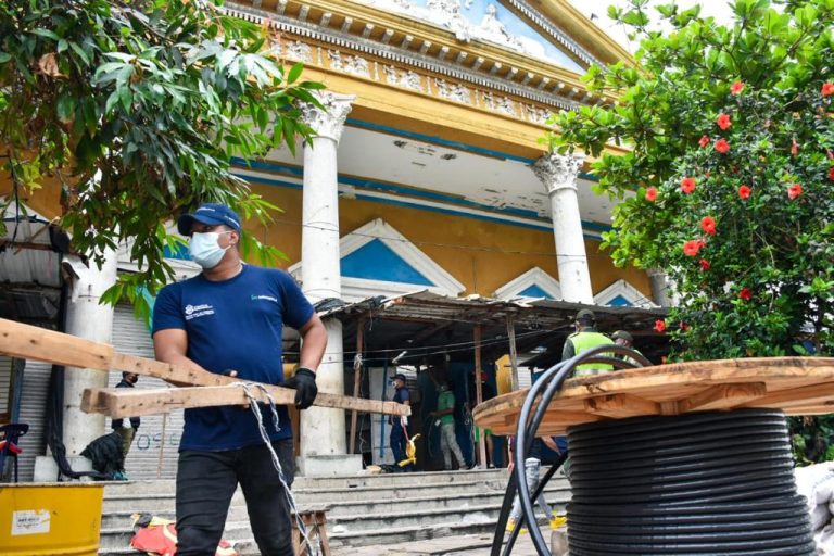 Funcionario cargando listones de madera en calle.