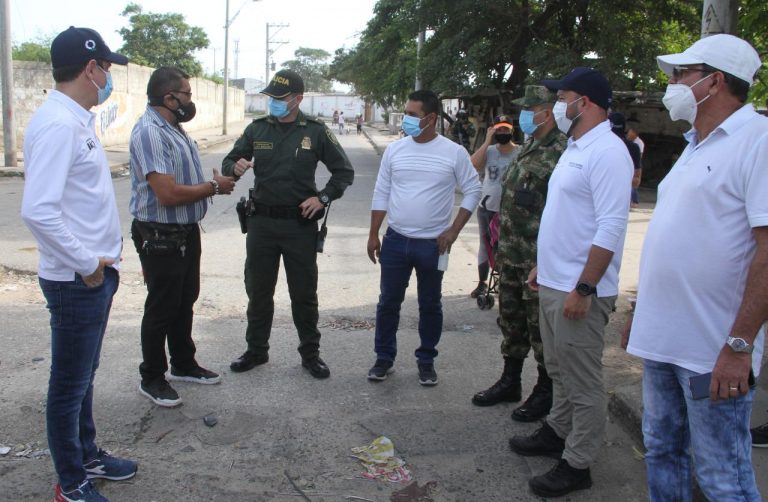 Funcionarios del distrito y fuerza pública, dialogando en una calle.