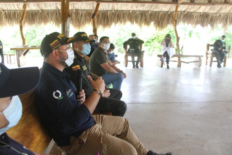 Funcionarios del distrito con policias reunidos con la comunidad en un kiosco