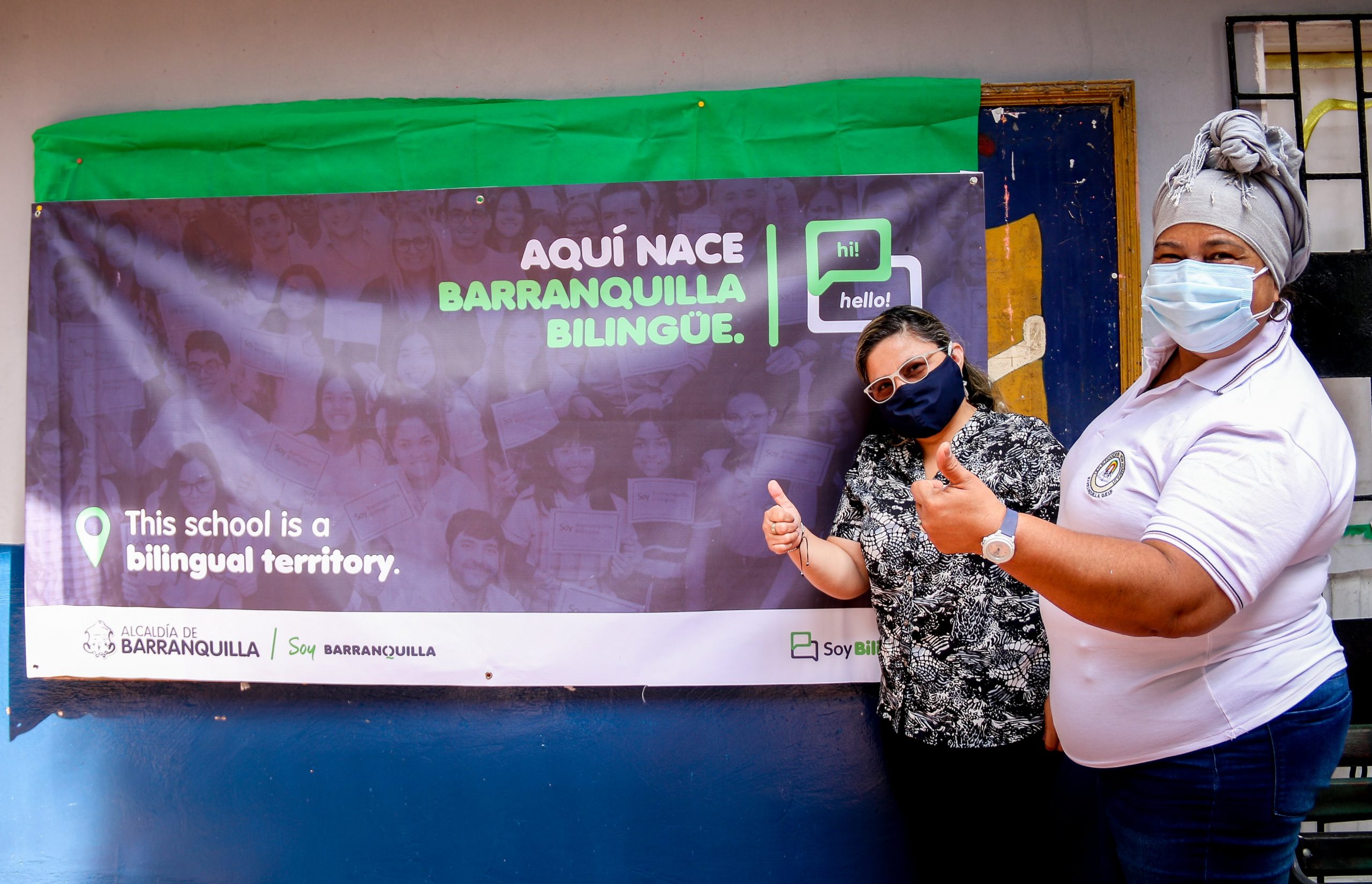 Funcionarios posando delante de cartel de Barranquilla Bilingue.