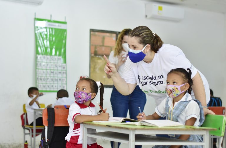 Profesora dando instrucciones a niños en salón de clases 