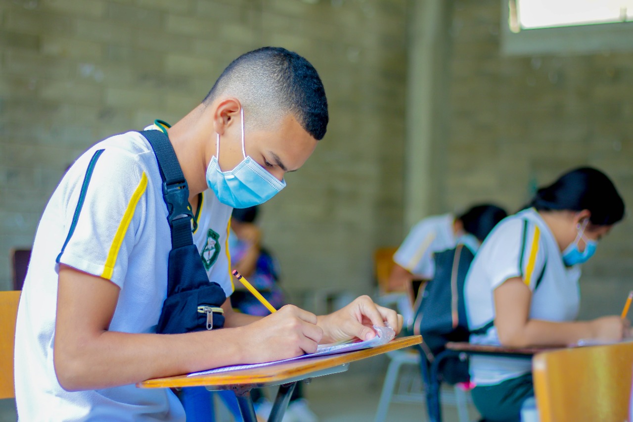 Estudiantes en salón de clases realizando examen.