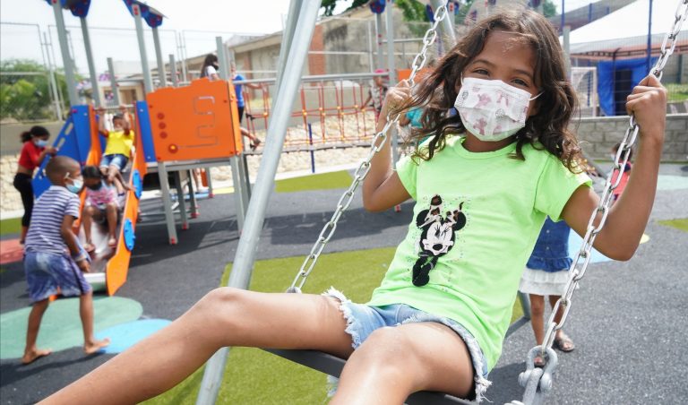 Niña en columpio en zona infantil. zona