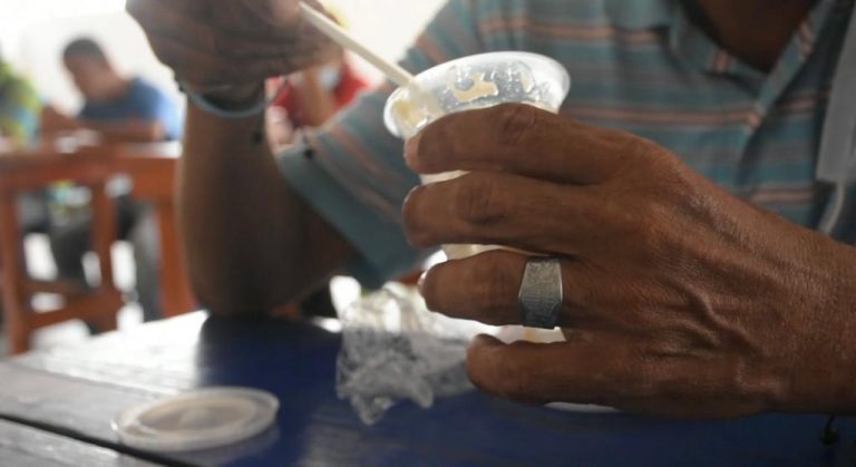 Manos sosteniendo vaso plástico y cuchara.