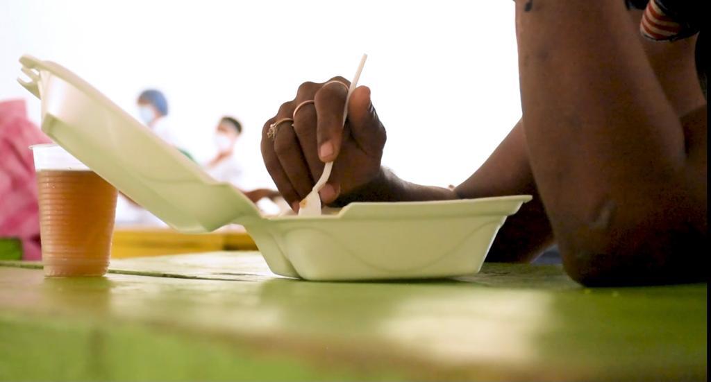 Brazos de una persona manipulando alimento en contenedor plástico.