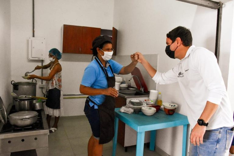 Funcionario saludando de puño a cocinera.