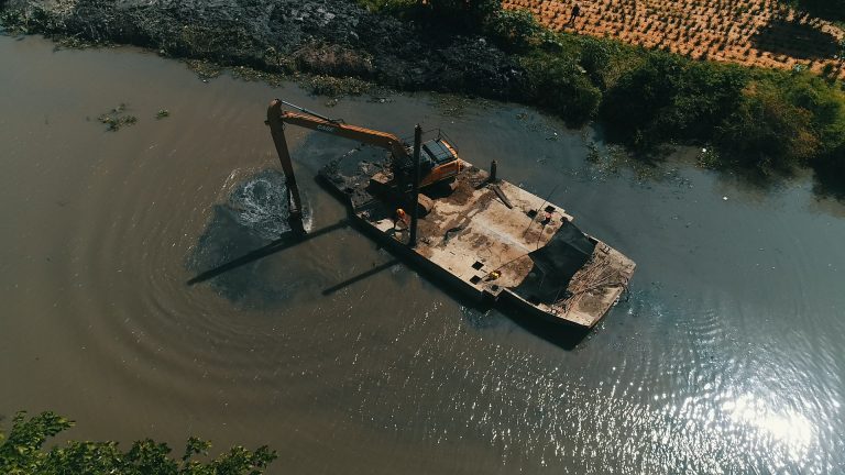 Foto aérea de Retroexcabadora sacando basura de caños.