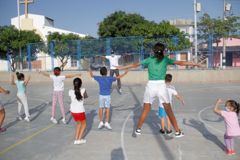 Instructor y niños realizando ejercicios.