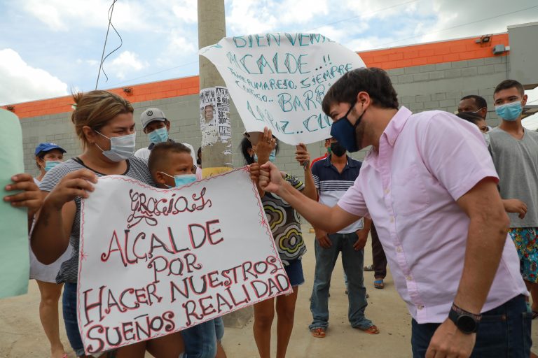 Alcalde Pumarejosaludando a mujer y niño con cartel de agradecimiento.