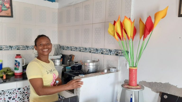 Ciudadana sonriendo en cocina de su casa.