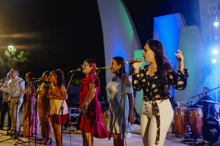 Grupo de mujeres y hombre cantando en concha custica de parque