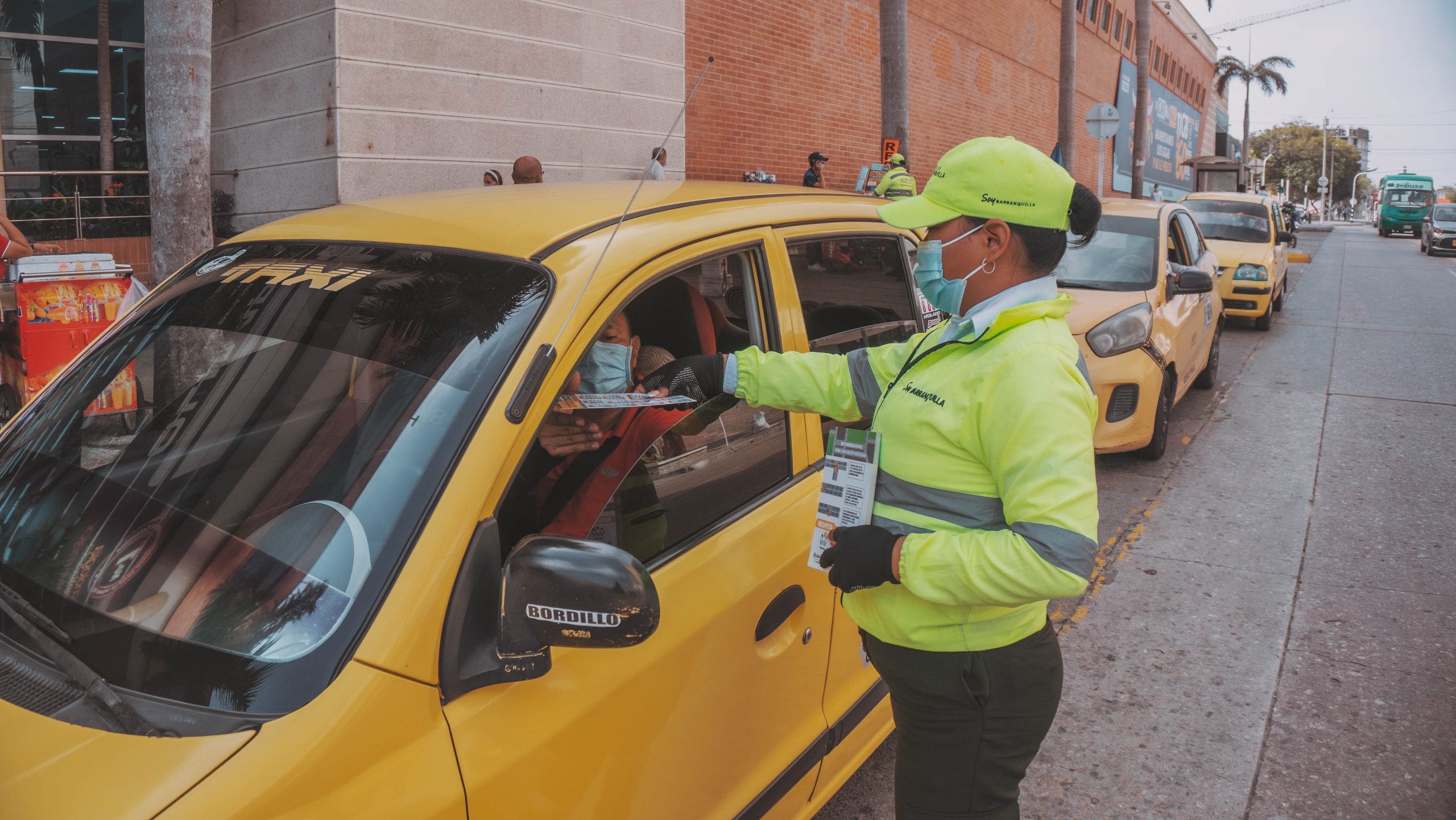 Orientdora de tránsito entregando volantes a taxistas.