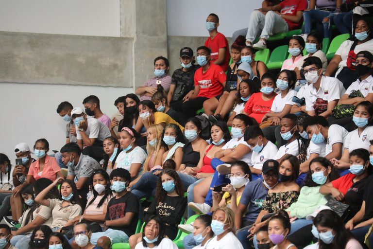 Grupo de ciudadanos en graderías de estadio recibiendo información.