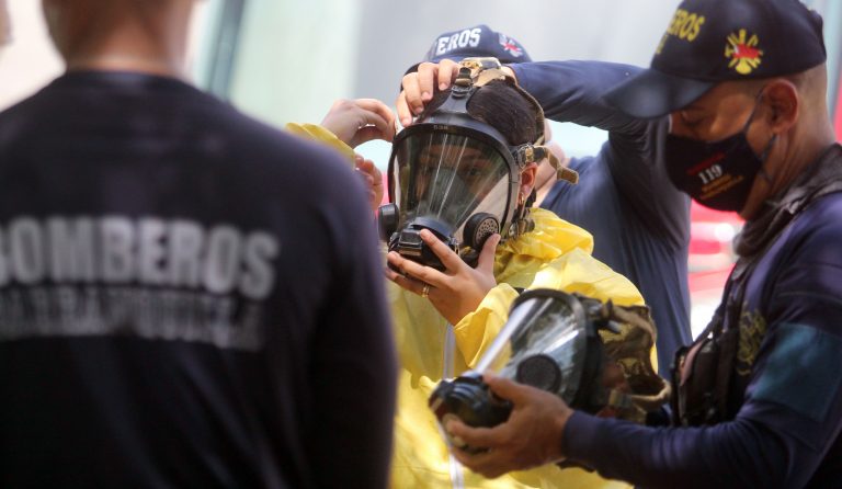 Bomberos colocan máscara contra incendios e indumentaria a mujer