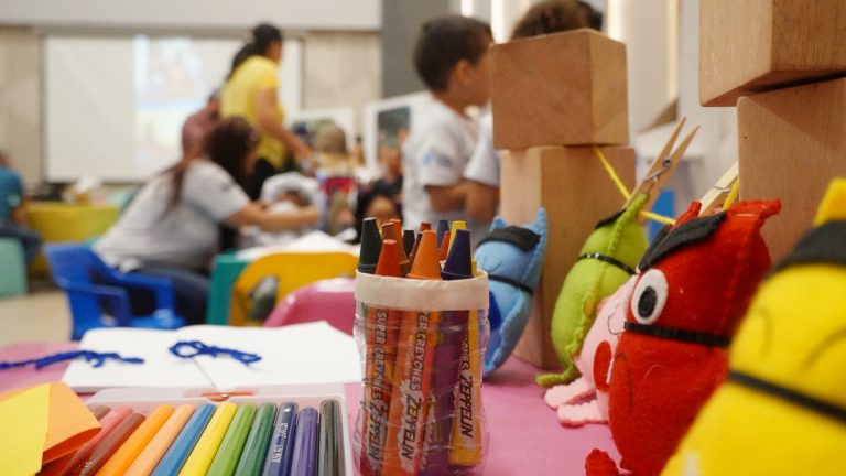 Lápices, crayones y títeres en una mesa en salón de clases