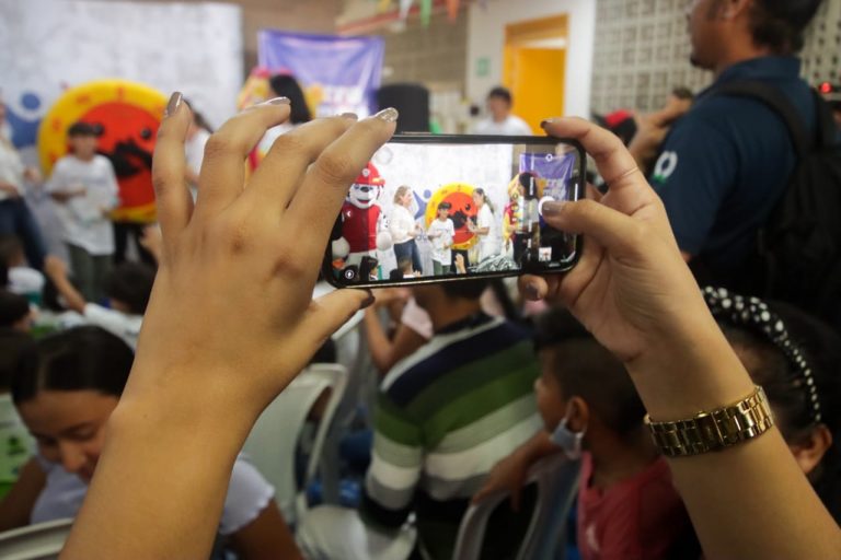 Mujer grabando en su celular evento estudiantil