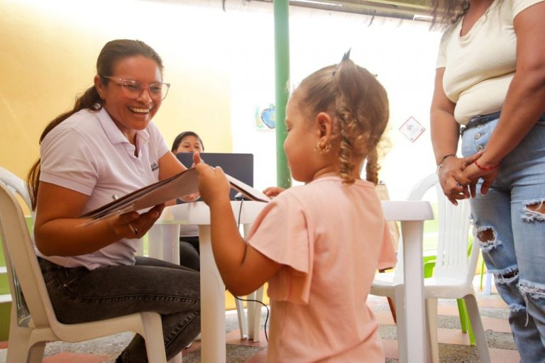 Niña recibiendo dibujos por parte de docente de CDI