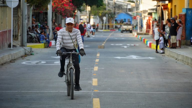 Joven manejando bicicleta sobre una de las calles recien pavimentadas por barrios a la obra