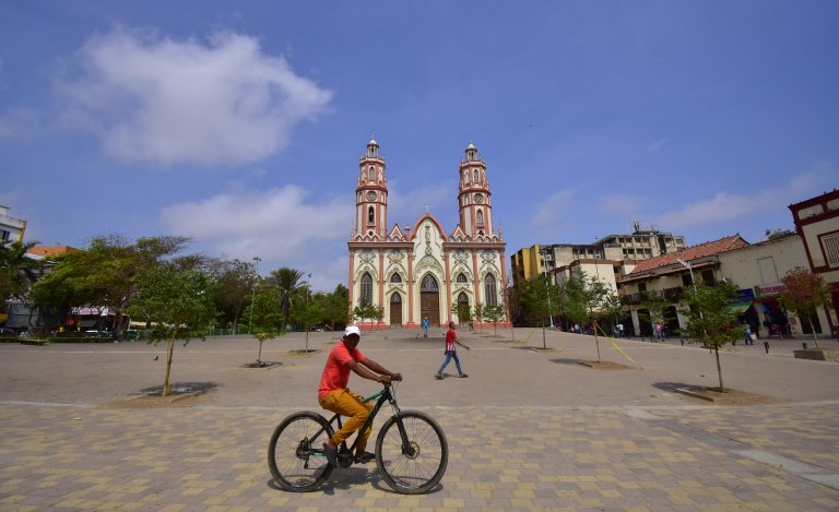 Panoramica de ciudadano paseando en bicicleta en la plaza de San Nicolas con la iglesia detrás