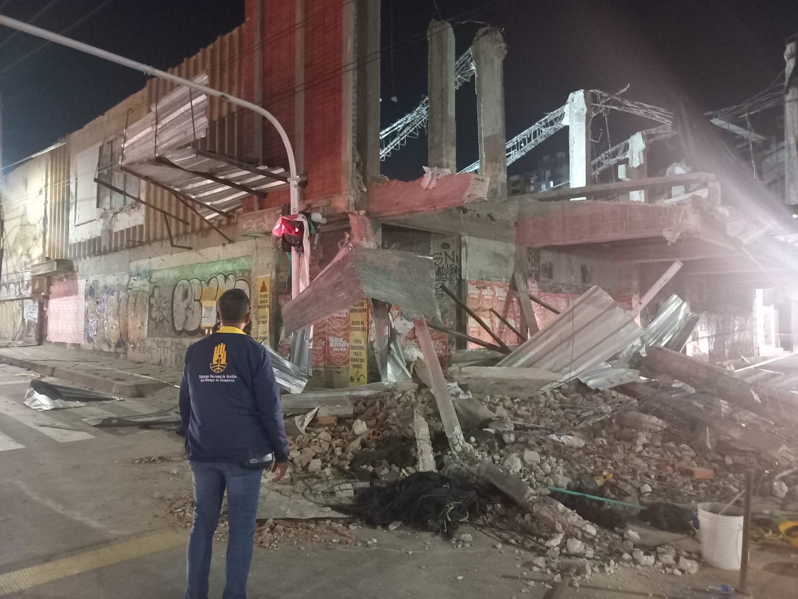 Funcionario Gestión Riesgo mirando hacia edificio en ruinas