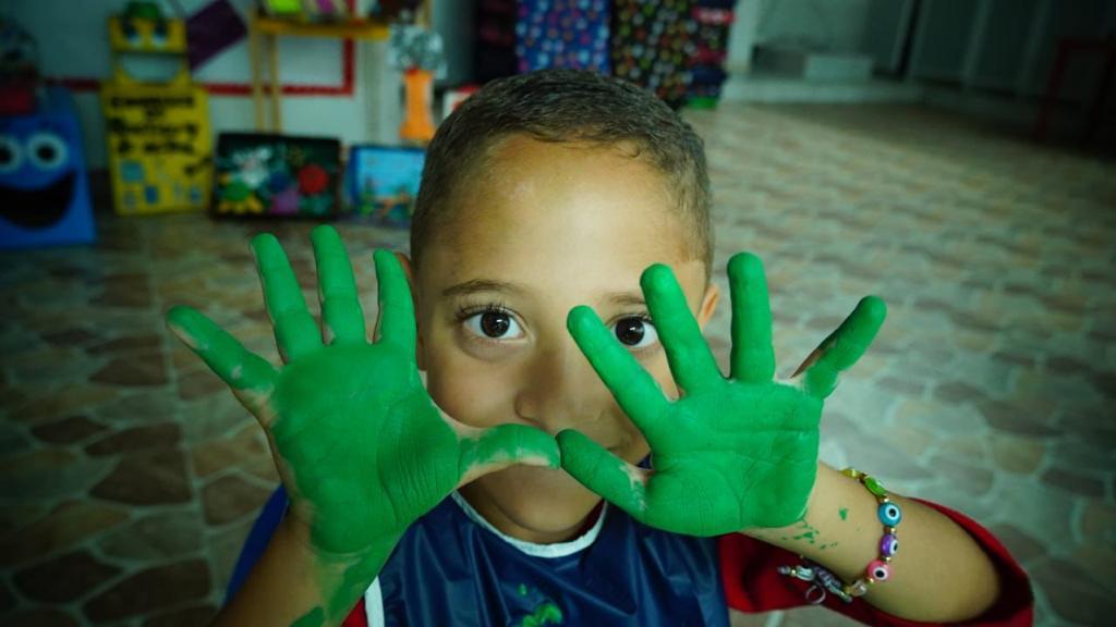 Niño mostrando las palmas de las manos pintadas de verde