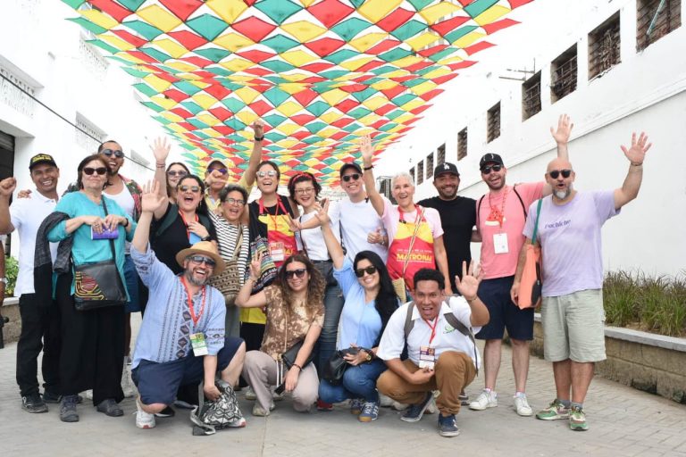 Grupo de personas posando con las manos extendidas en un callejón con techo de paraguas