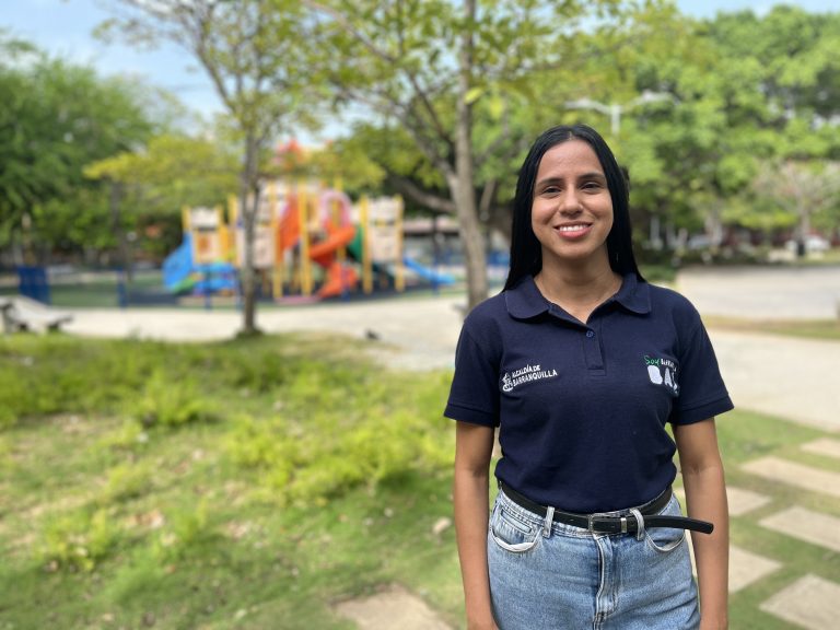 funcionaria con camiseta institucional de pie en parque 