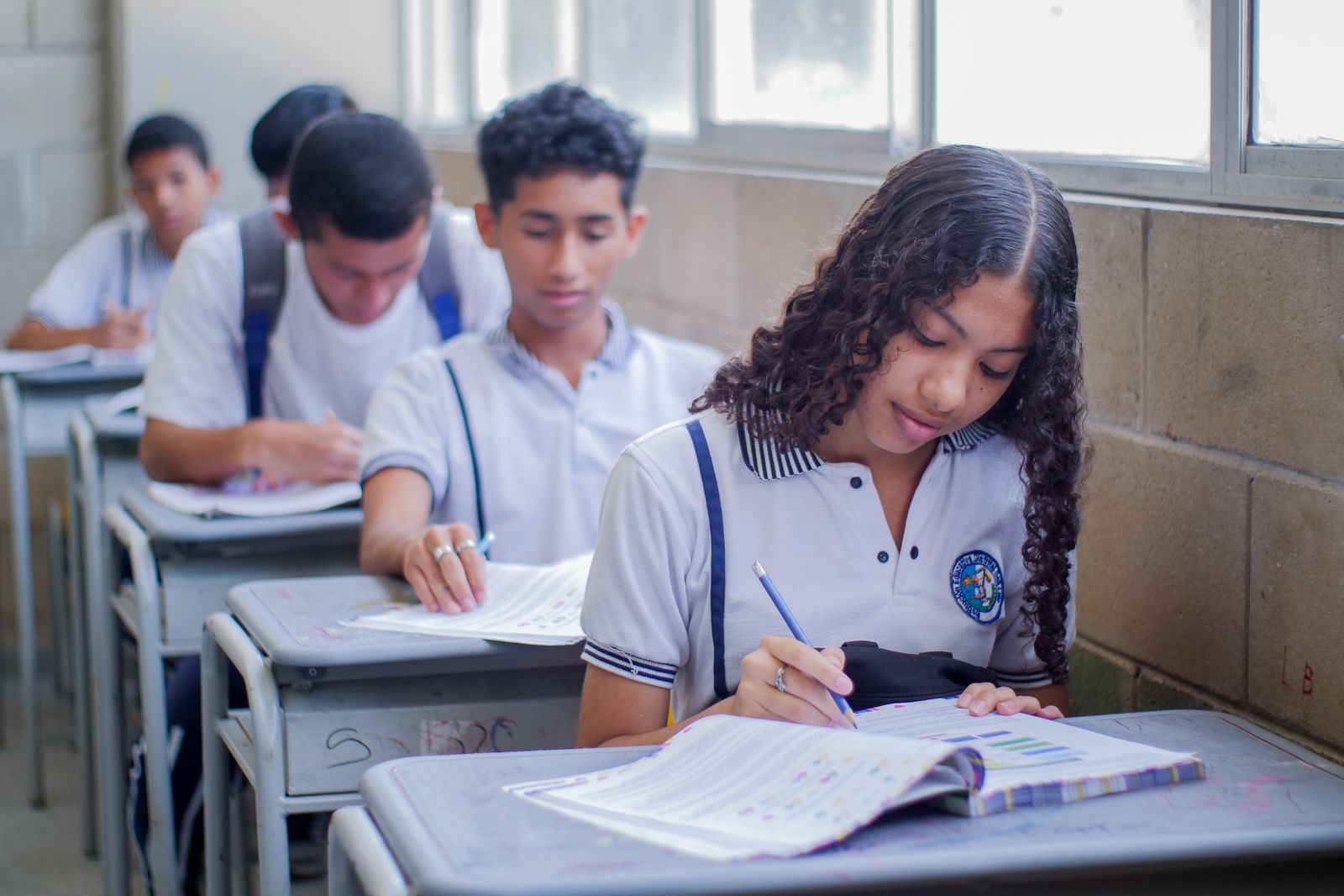 Estudiantes en pupitre haciendo prueba