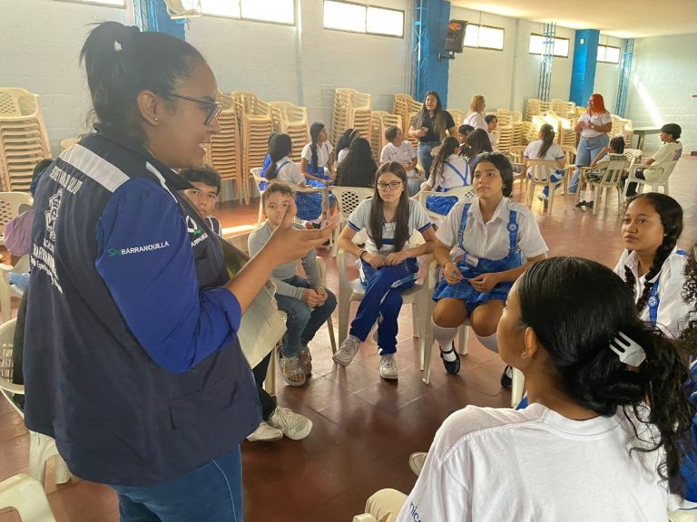 Funcionaria charla con un grupo de estudiantes en aula de clase